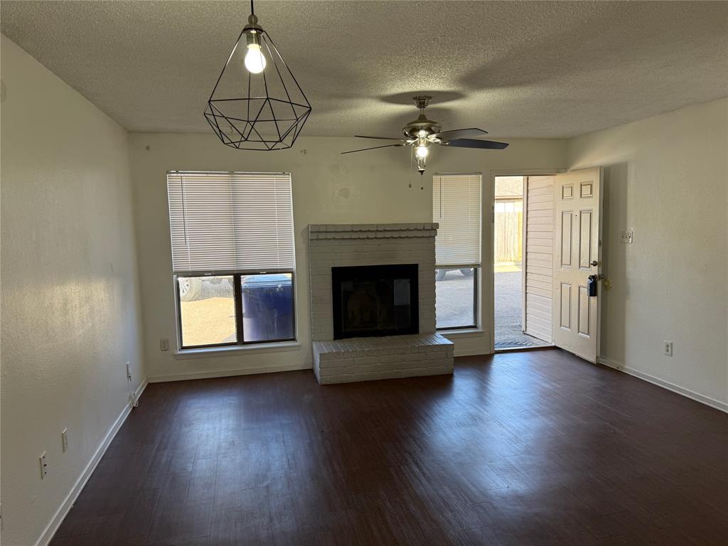 422 West 4th Street Kennedale, TX 76060 - Photo 4 of 25 an empty room with wooden floor fireplace and windows