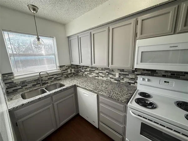 a kitchen with granite countertop a sink stove and cabinets