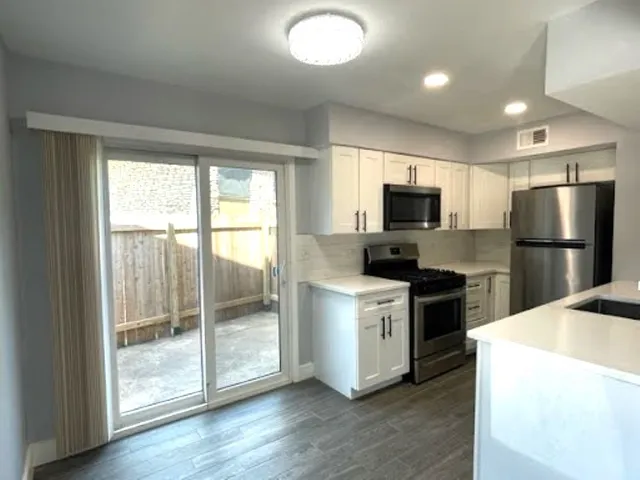 a kitchen with granite countertop a refrigerator and a stove top oven