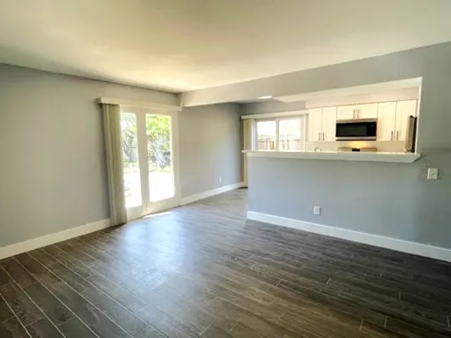 a view of empty room with wooden floor and window