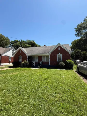 a front view of a house with yard and car parked
