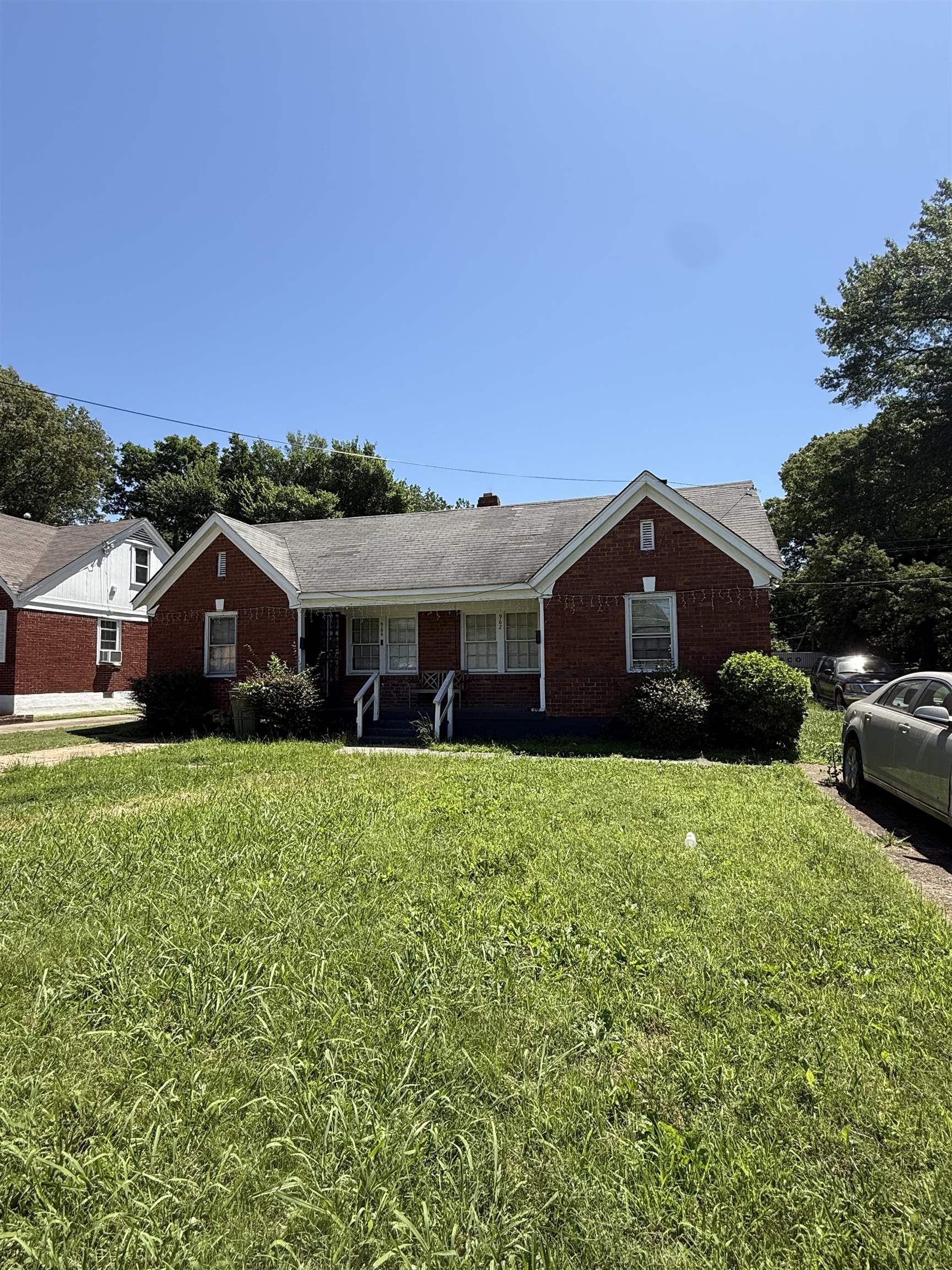 a front view of a house with yard and car parked