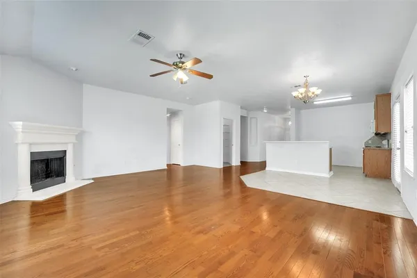 a view of an empty room with a fireplace and wooden floor