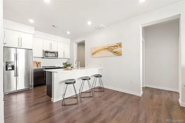 a kitchen with stainless steel appliances granite countertop a refrigerator a stove a sink dishwasher and white countertops with wooden floor