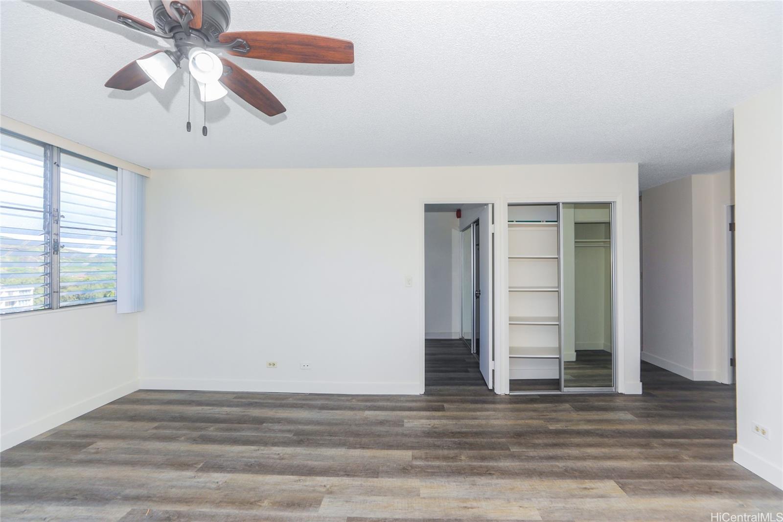 2977 Ala Ilima Street, Unit 610 Honolulu, HI 96818 - Photo 5 of 25 an empty room with wooden floor chandelier fan and windows