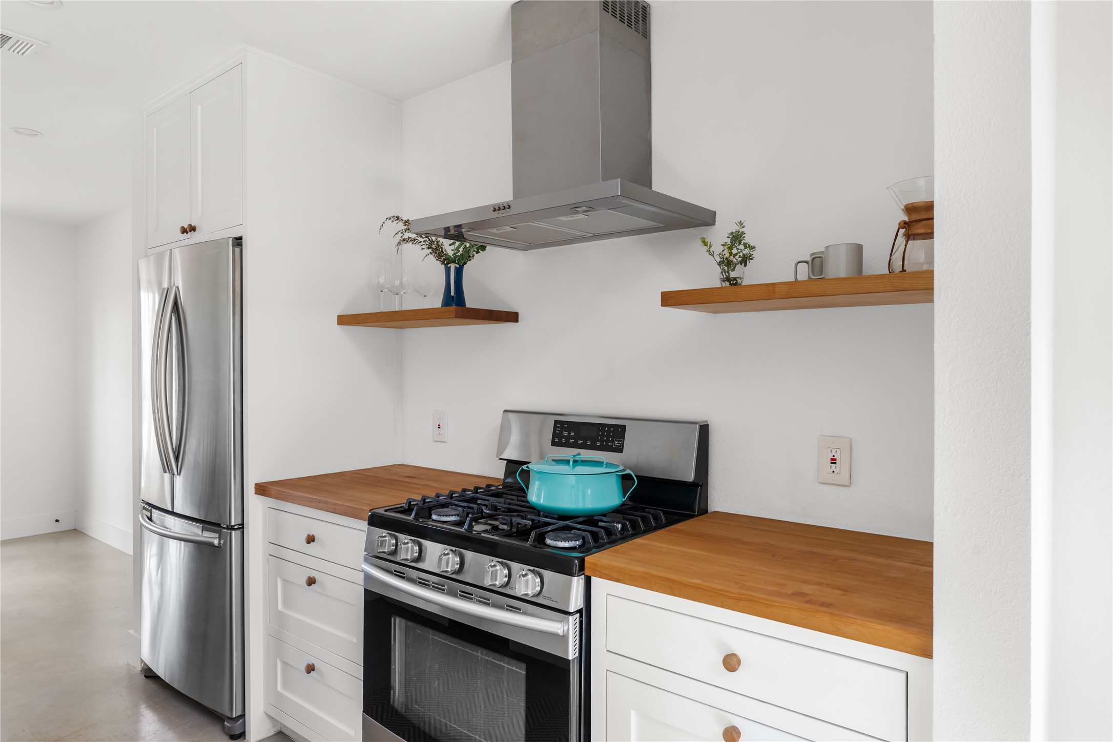 400 Delmar Avenue Austin, TX 78752 - Photo 20 of 36 A clean mix of stainless steel appliances, open shelving, white cabinets, and warm maple butcher block countertops with wood knobs