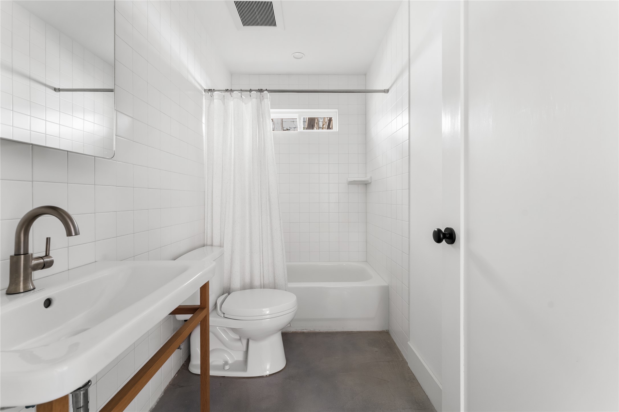 400 Delmar Avenue Austin, TX 78752 - Photo 28 of 36 Minimal and understated guest bathroom, featuring classic white tile and a warm wood vanity detail