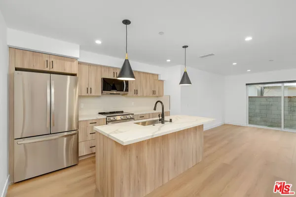 a kitchen with stainless steel appliances granite countertop a refrigerator a sink dishwasher a stove and a refrigerator