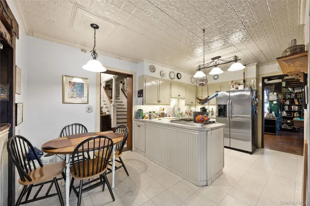 a kitchen with stainless steel appliances kitchen island granite countertop dining table chairs and a refrigerator