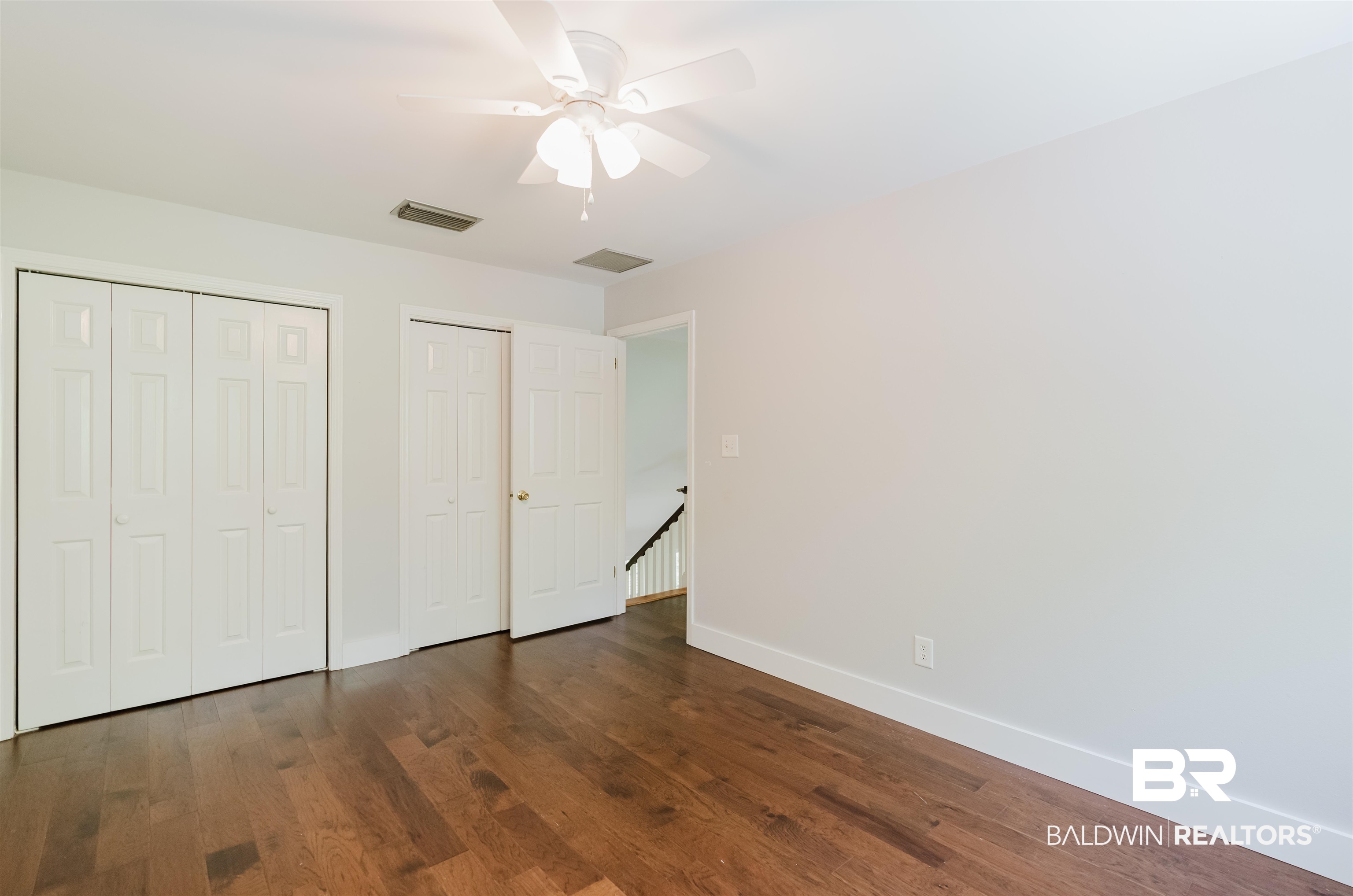 20460 Bishop Road Fairhope, AL 36532 - Photo 25 of 41 Unfurnished bedroom with two closets, baseboards, wood finished floors, and a ceiling fan