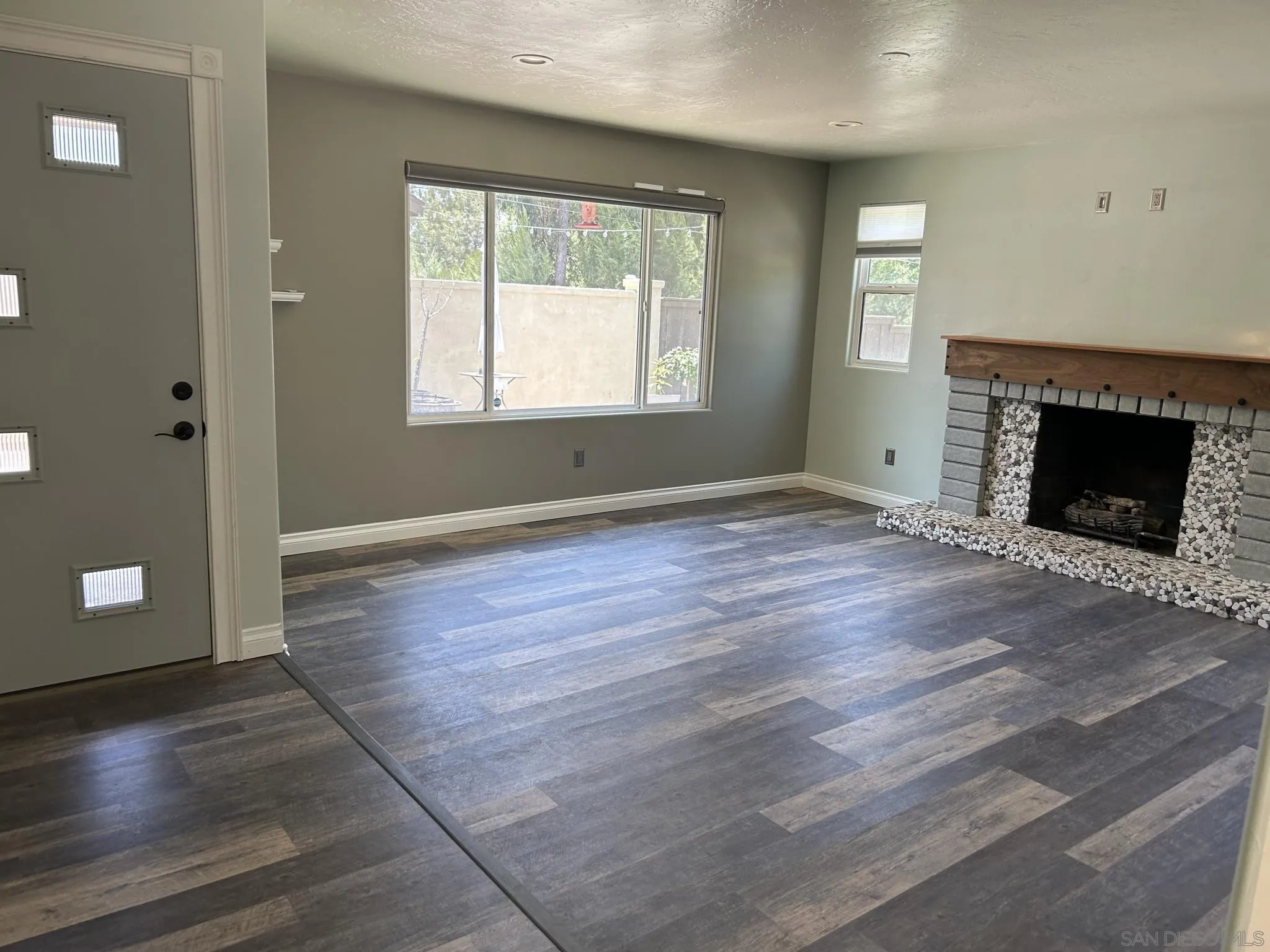 15408 Espola Road Poway, CA 92064 - Photo 13 of 27 an empty room with wooden floor fireplace and windows