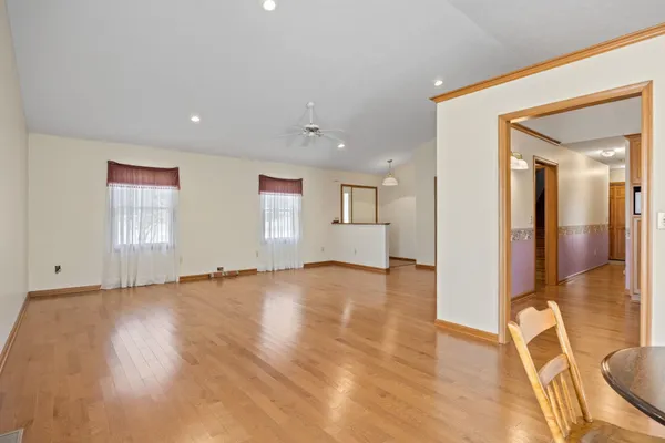 a view of an empty room with wooden floor and a bathroom