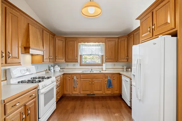 a kitchen with granite countertop a refrigerator a sink a stove and white cabinets