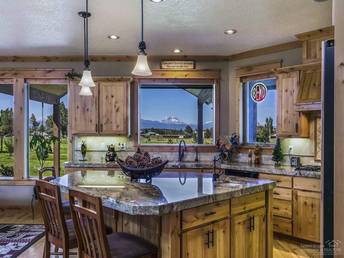 20200 Marsh Road Bend, OR 97703 - Photo 9 of 25 a kitchen with granite countertop a stove a sink and a dining table with chairs