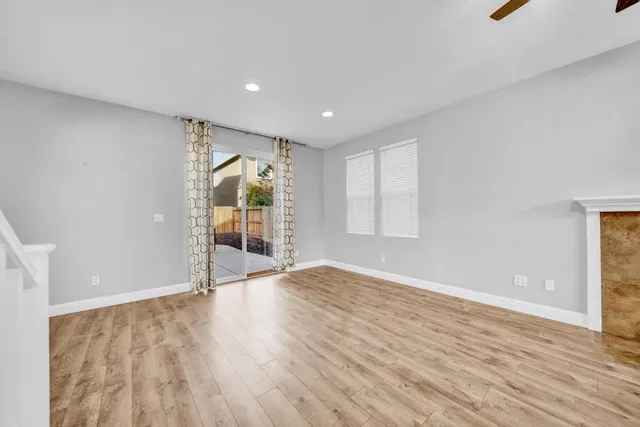a view of a kitchen and an empty room with wooden floor and a window