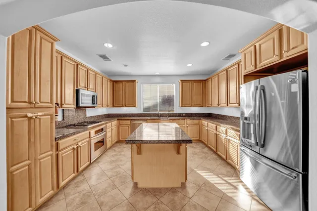 a kitchen with stainless steel appliances granite countertop a sink a stove and a refrigerator