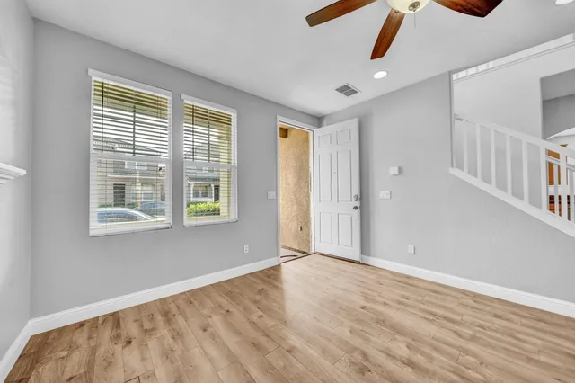 an empty room with wooden floor fireplace and windows