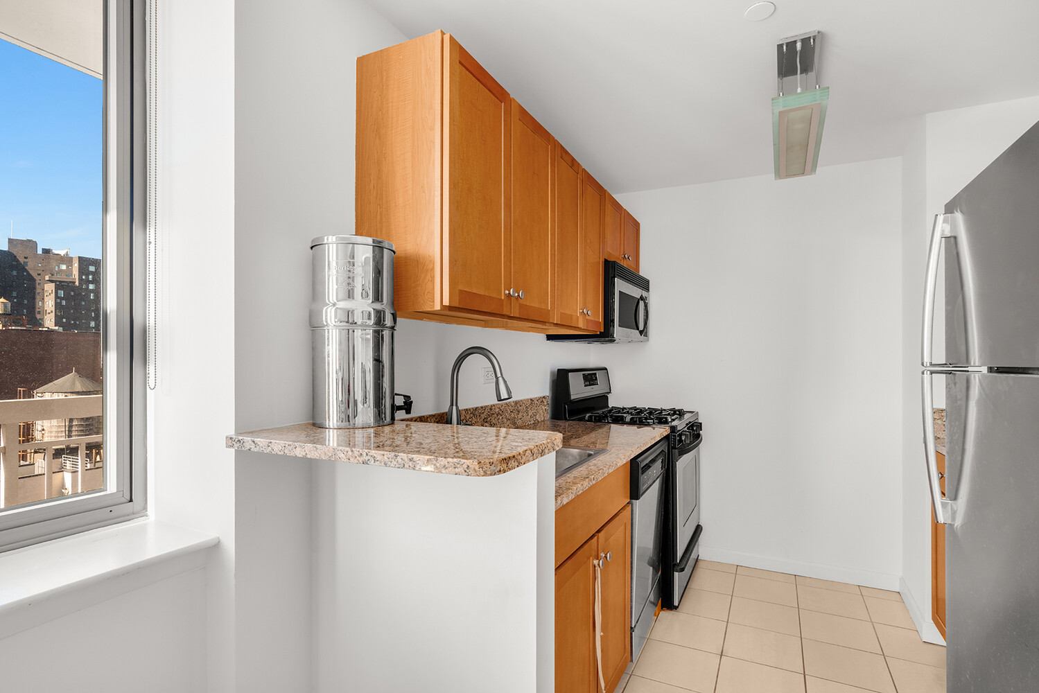 520 West 23rd Street, Unit 14G Manhattan, NY 10011 - Photo 4 of 7 a kitchen with stainless steel appliances granite countertop a refrigerator a stove a sink and a microwave