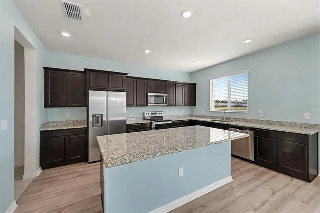 a large kitchen with granite countertop a refrigerator and a stove top oven