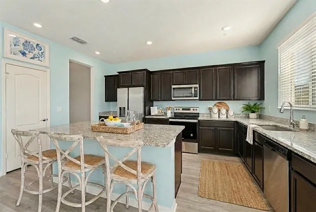 a kitchen with granite countertop wooden cabinets a counter top space and stainless steel appliances