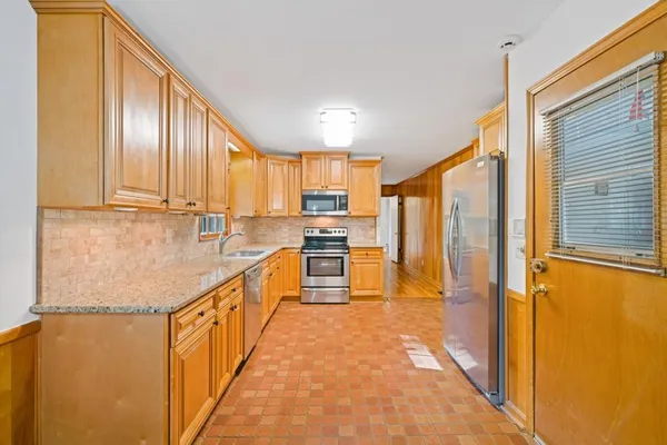 a kitchen with stainless steel appliances granite countertop a refrigerator a stove and a sink with wooden floor