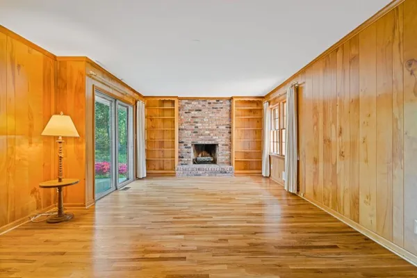 a view of an empty room with wooden floor and a fireplace