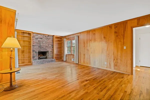 a view of an empty room with wooden floor and a fireplace