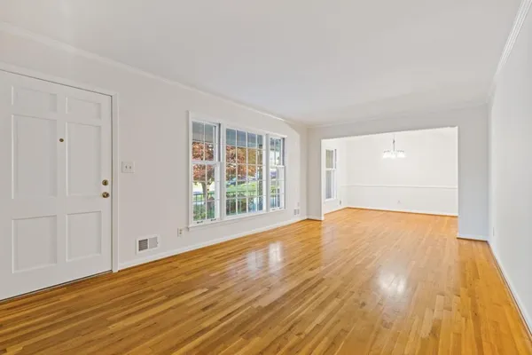a view of an empty room with wooden floor and a window