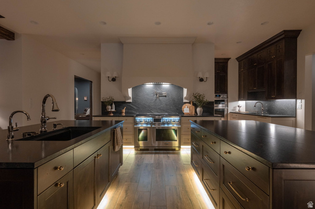4871 South Homestead Way Washington, UT 84780 - Photo 100 of 151 Kitchen with dark wood finish cabinets, a center island with sink, decorative backsplash, and stainless steel appliances