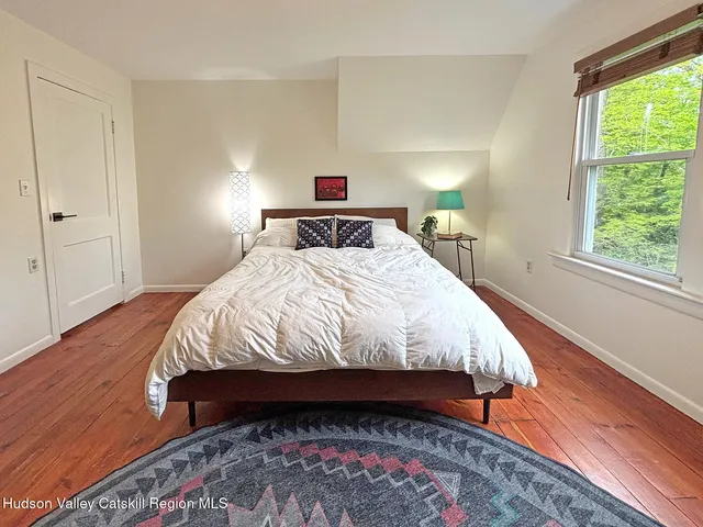 a bedroom with a bed lamps and wooden floor