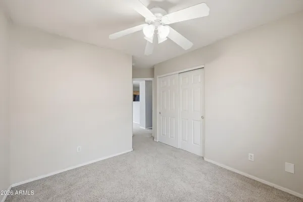 an empty room with a chandelier fan and closet
