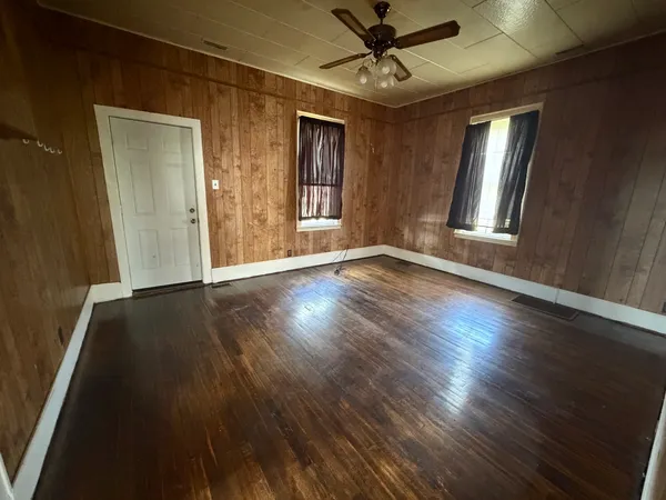 a view of an empty room with wooden floor and a window