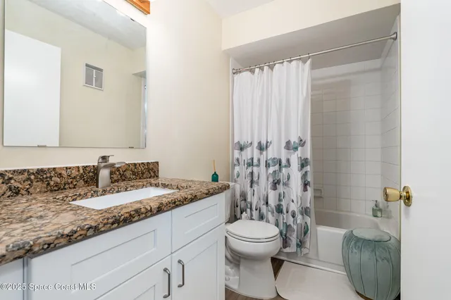 a bathroom with a granite countertop sink a toilet and shower