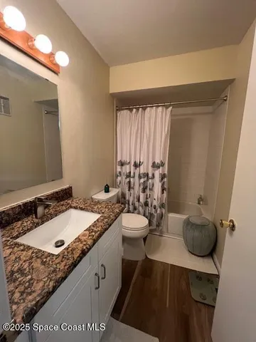 a bathroom with a granite countertop sink a toilet and a mirror