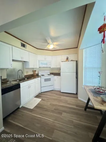 a kitchen with a white stove top oven and white cabinets with wooden floor
