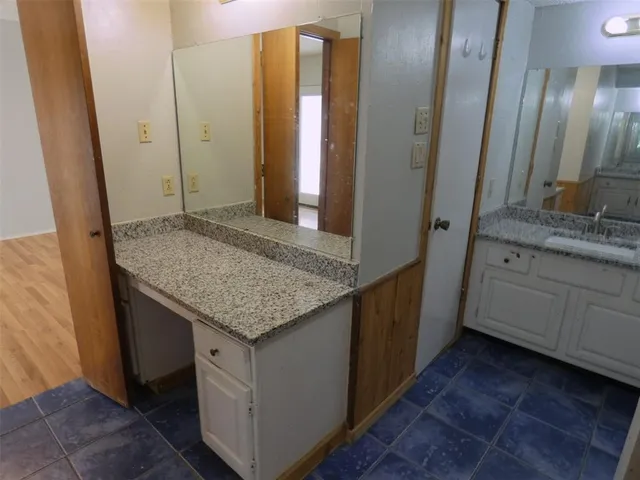 a bathroom with a granite countertop sink and a mirror