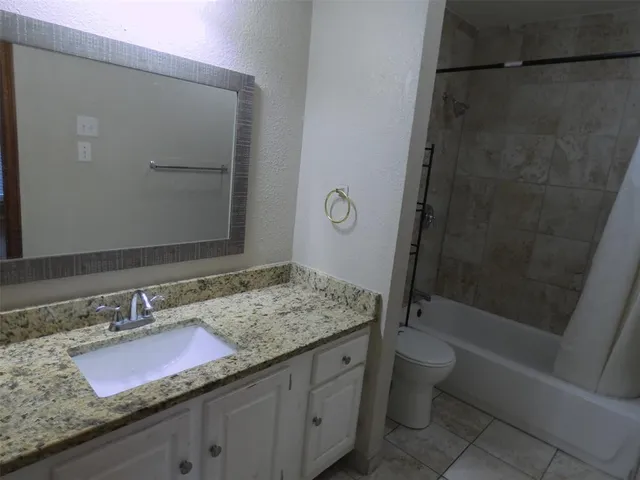 a bathroom with a granite countertop sink a toilet and bathtub