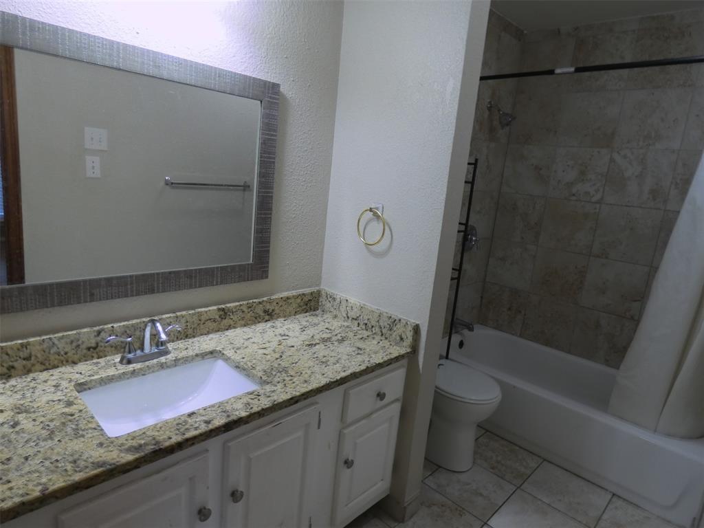 7110 Ridgeview Drive Rowlett, TX 75089 - Photo 23 of 27 a bathroom with a granite countertop sink a toilet and bathtub