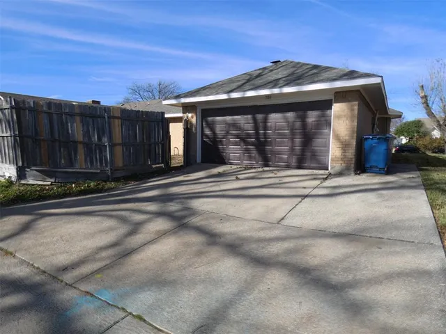a front view of a house with a garden and wooden fence