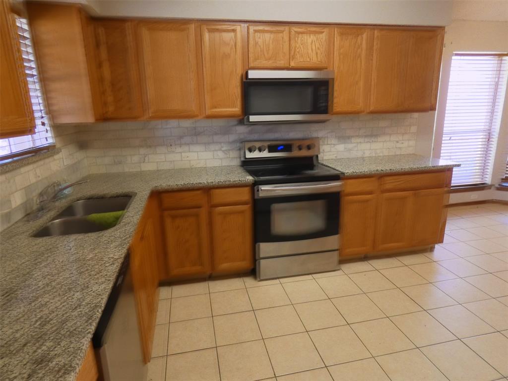 7110 Ridgeview Drive Rowlett, TX 75089 - Photo 9 of 27 a kitchen with granite countertop a sink a stove top oven and cabinetry