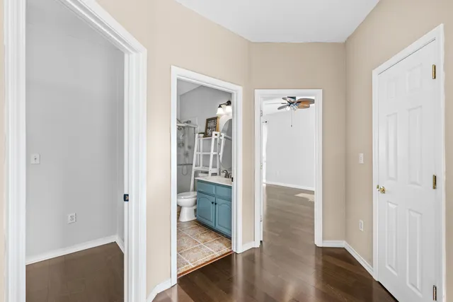 a view of a hallway with wooden floor a bathroom and a sink