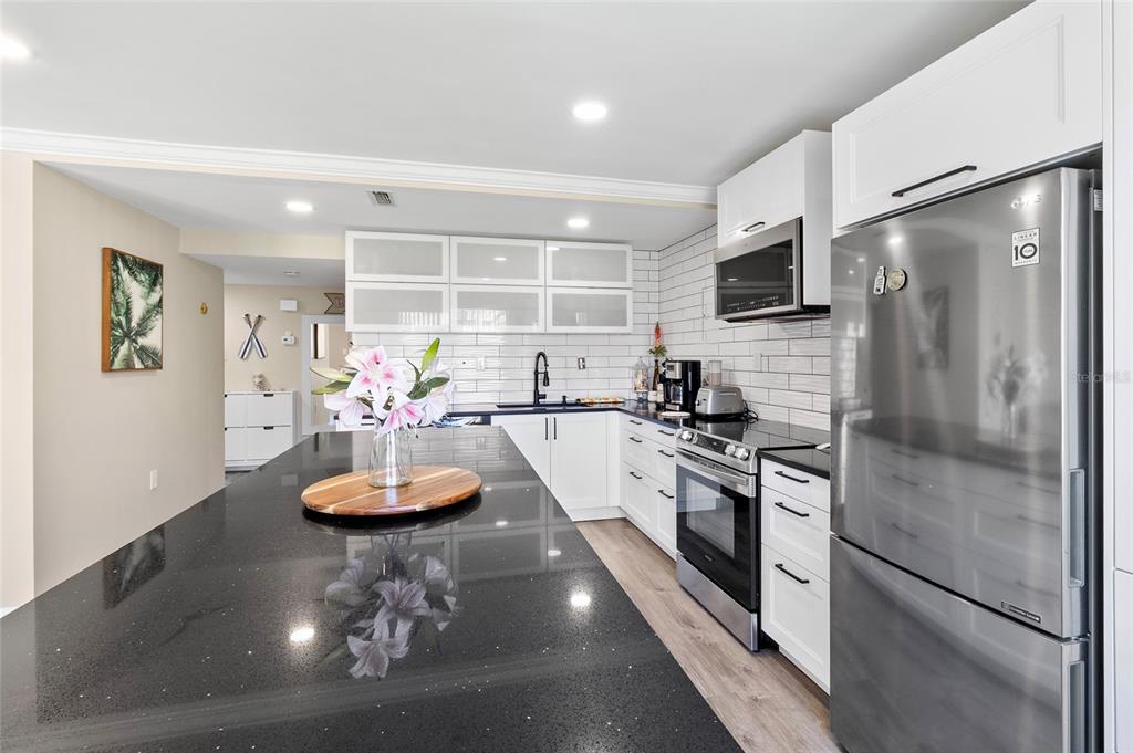 1579 Greenlea Drive, Unit 12 Clearwater, FL 33755 - Photo 6 of 42 a kitchen with stainless steel appliances granite countertop a refrigerator a stove a sink a dining table and chairs with wooden floor