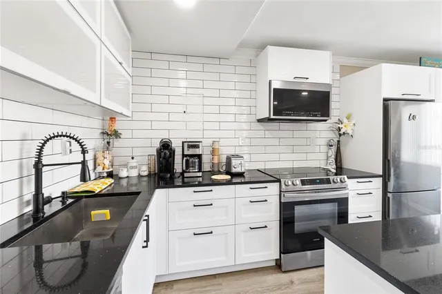 a kitchen with stainless steel appliances a stove sink and white cabinets