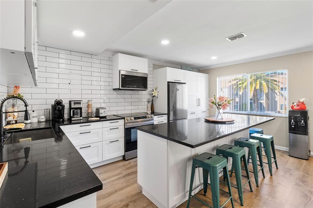 1579 Greenlea Drive, Unit 12 Clearwater, FL 33755 - Photo 9 of 42 a kitchen with stainless steel appliances granite countertop a sink a stove a refrigerator cabinets and chairs