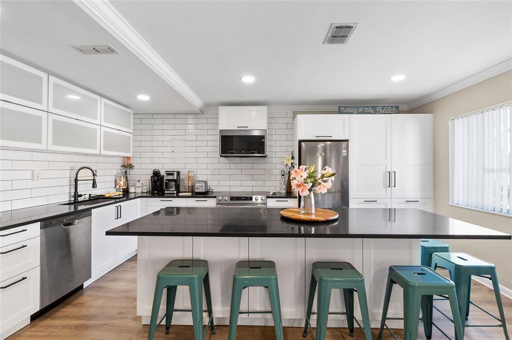 1579 Greenlea Drive, Unit 12 Clearwater, FL 33755 - Photo 10 of 42 a kitchen with white cabinets a sink stove and refrigerator with wooden floor