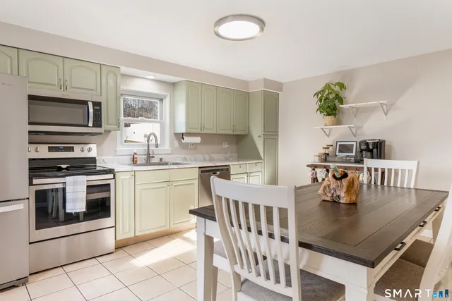 a kitchen with stainless steel appliances granite countertop a stove a sink a microwave a dining table and chairs