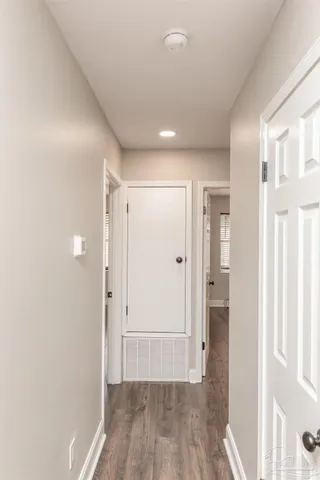 a view of a hallway with wooden floor and a bathroom