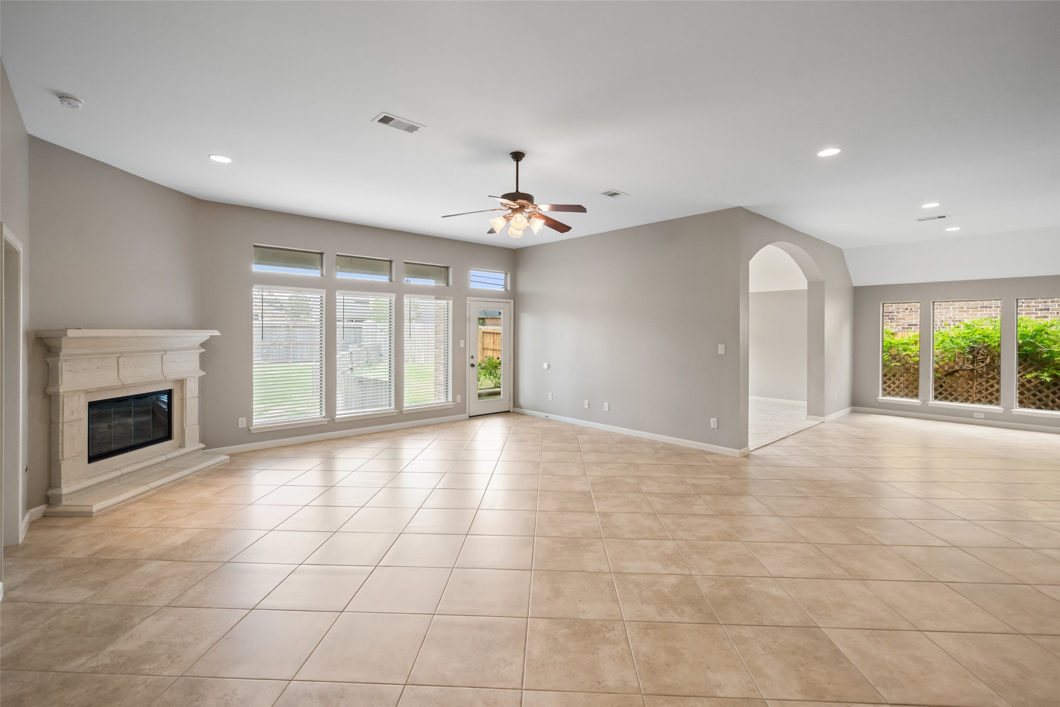 2818 Red Maple Drive Katy, TX 77494 - Photo 24 of 50 This spacious living area features a tiled floor, a cozy fireplace, and ample natural light from large windows. Neutral walls and recessed lighting create a modern, inviting atmosphere, perfect for family gatherings.