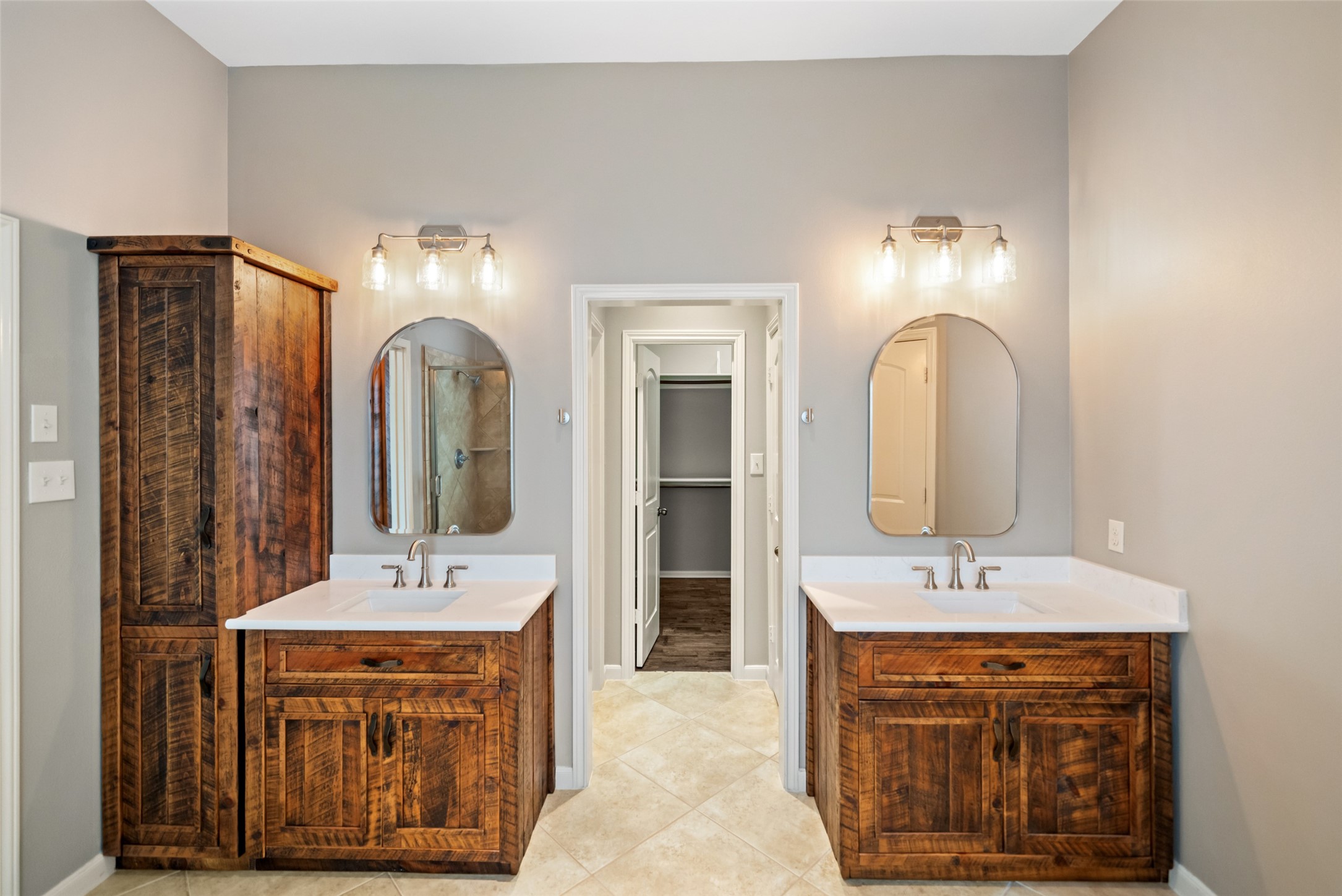 2818 Red Maple Drive Katy, TX 77494 - Photo 36 of 50 Primary Bathroom features dual sinks with stylish wooden cabinetry, modern lighting fixtures, and a neutral color palette. A central doorway leads to a spacious walk-in closets.