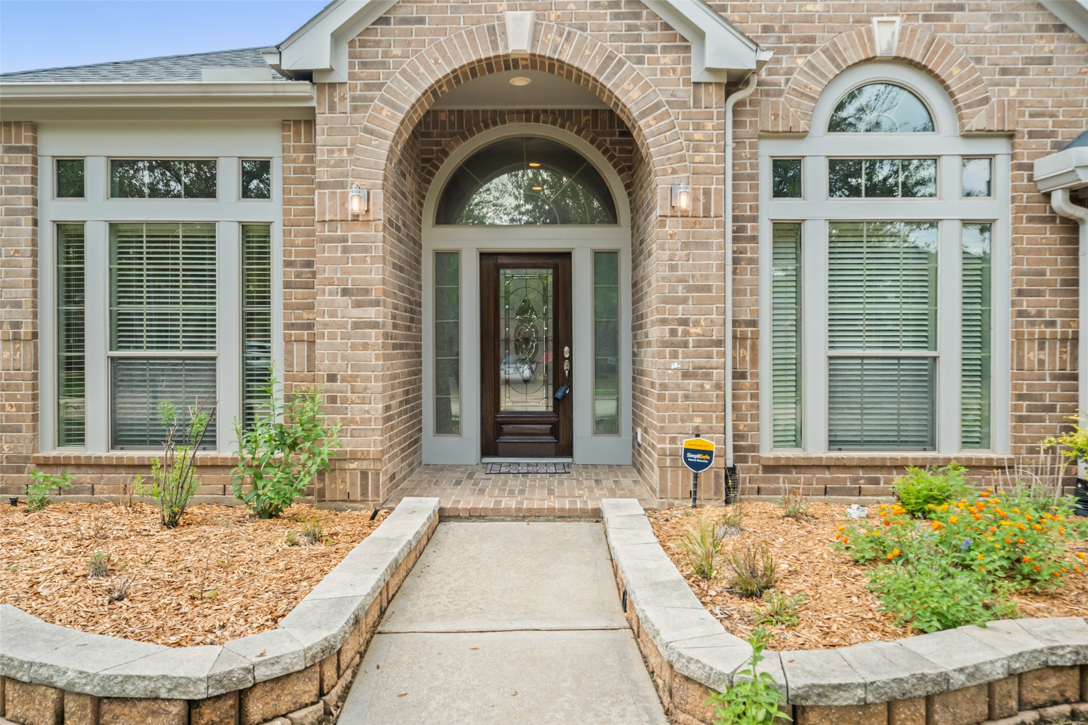 2818 Red Maple Drive Katy, TX 77494 - Photo 4 of 50 Charming arched entrance and elegant glass door. The front features well-maintained landscaping with a stone-bordered garden, enhancing curb appeal. Large windows provide ample natural light.